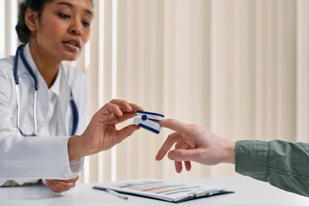 Doctor measures patient's blood oxygen with a pulse oximeter.
