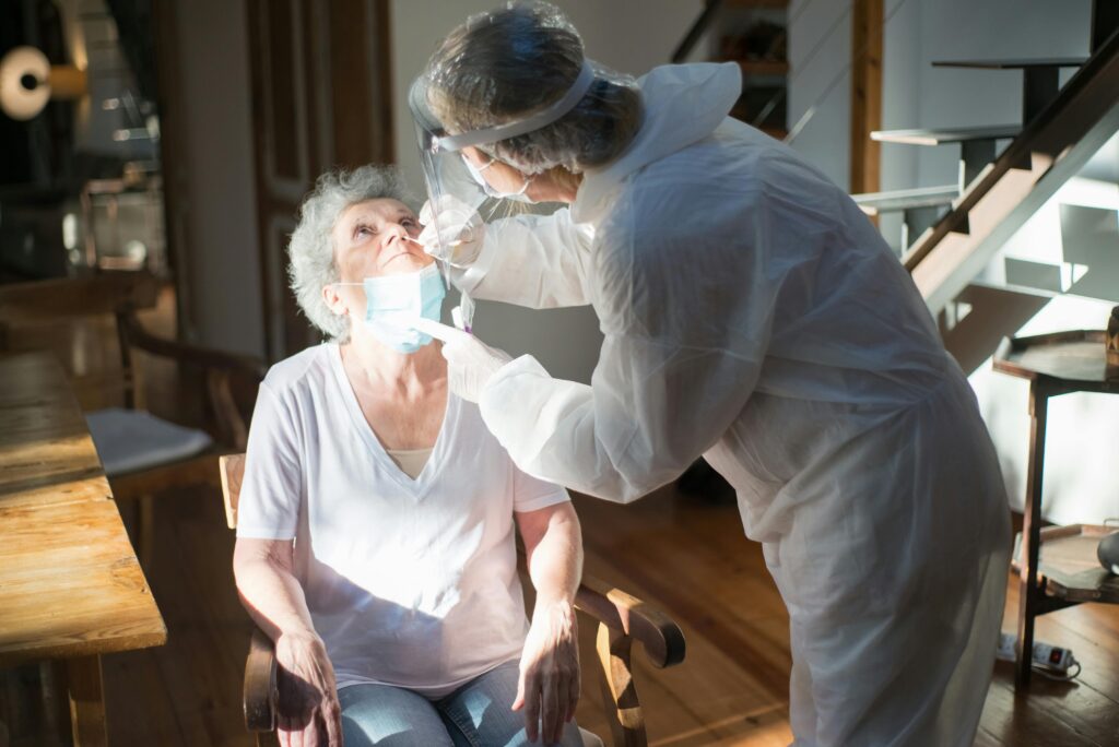 A healthcare worker performs a COVID-19 test on an elderly woman.
