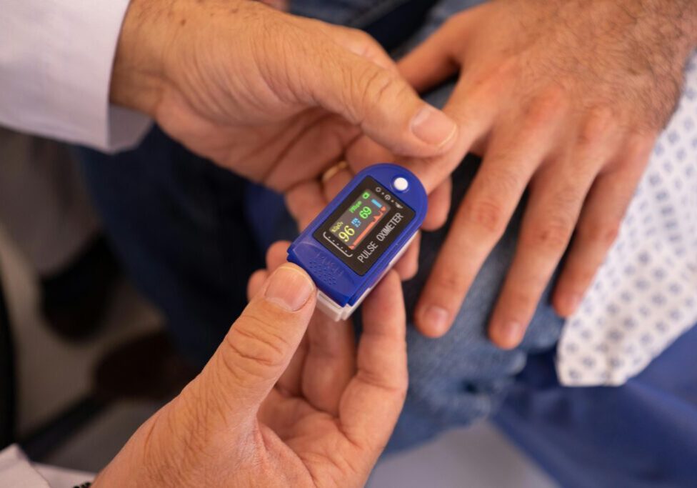 Person using a fingertip pulse oximeter to check oxygen levels.